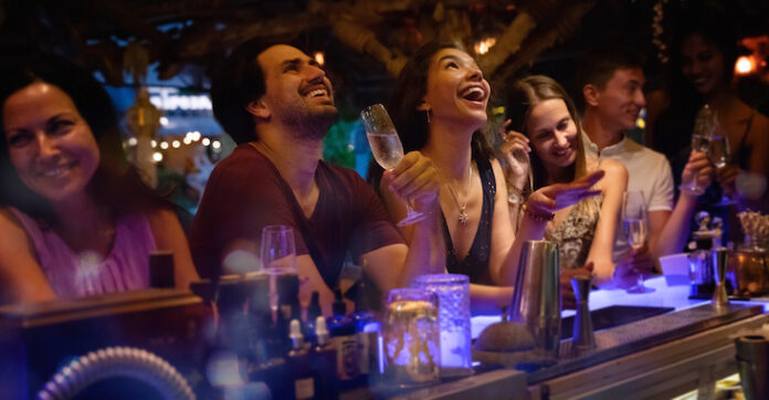 Group of young people having fun at a party at the bar, laughing and drinking alcohol
