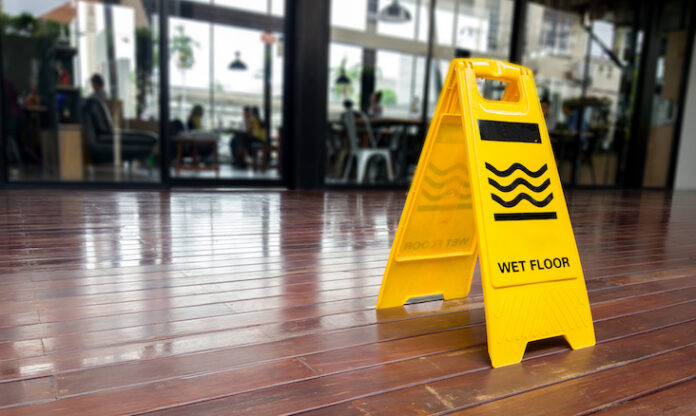yellow plastic cone with sign showing warning of wet floor in restaurant