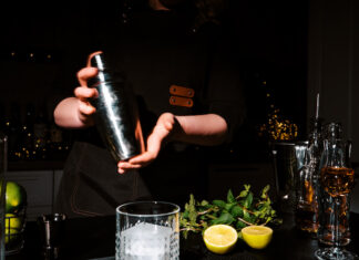 Movers and Shakers: The Class of 2026 Woman bartender shaking cocktail in metal shaker with two hands. Intensive mixing process for refreshing drink and nightlife entertainment concept.